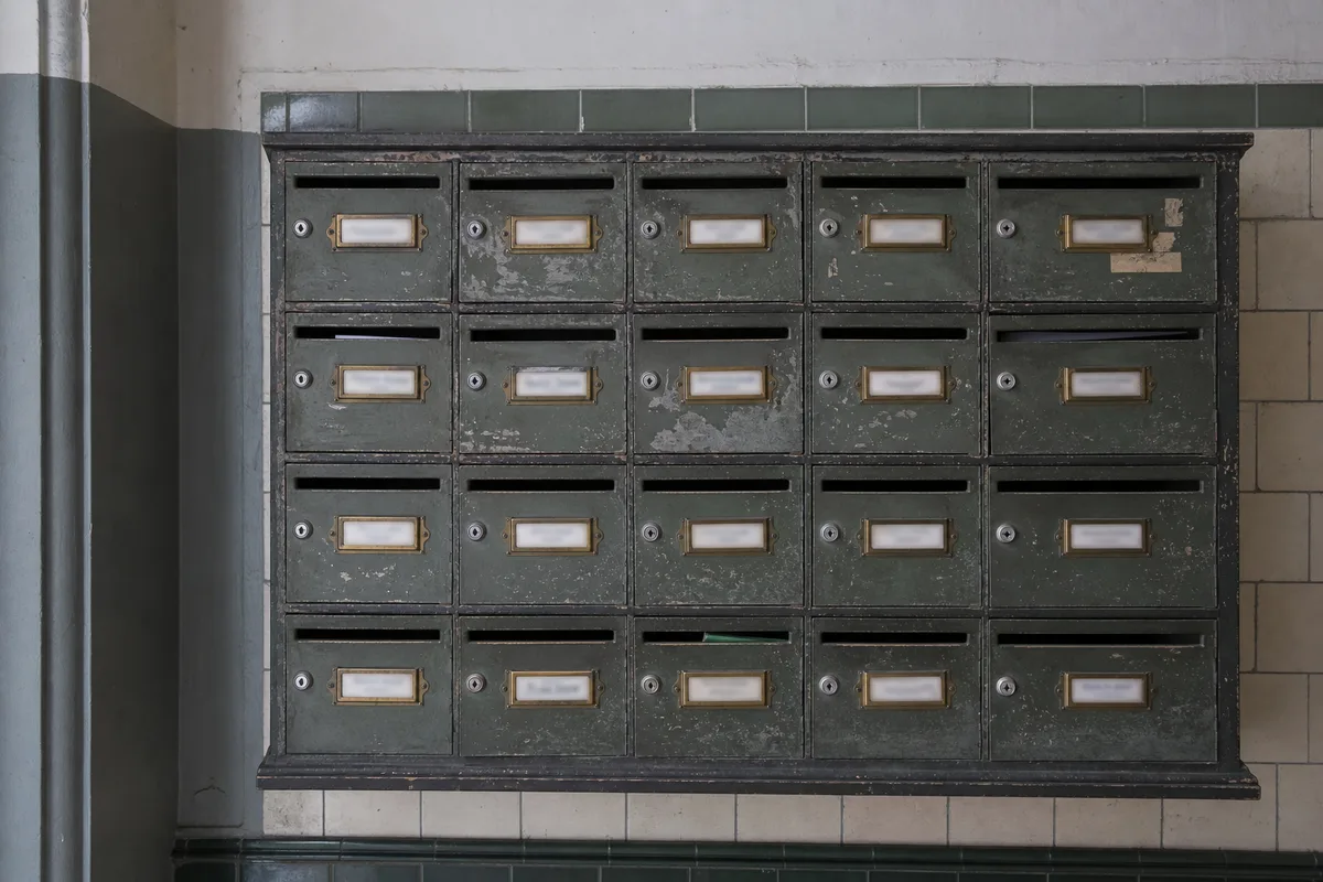 Boîte aux lettres collective d&rsquo;un immeuble berlinois avec des étiquettes de noms manuscrites et imprimées